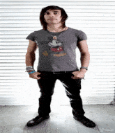 a man wearing a mickey mouse shirt is standing in front of a wall