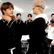 a group of young men are hugging each other and one of them has a mask on his face