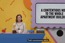 a woman sits at a desk with a sign that says a contentious no to the whole apartment building