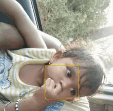 a little girl with a yellow square around her face is wearing a shirt that says tg
