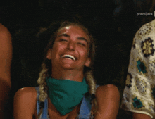 a woman wearing a green bandana is laughing in front of a sign that says premiere