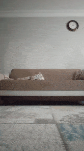 a couch in a living room with a clock hanging on the wall