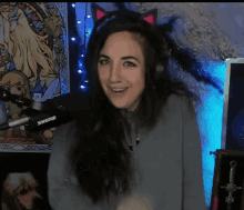 a woman wearing headphones and a cat ear headband is standing in front of a shure microphone