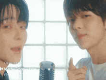 two young men are standing next to each other and one is pointing