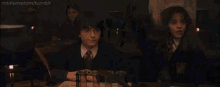 hermione granger is sitting in front of a microphone in a classroom with her eyes closed .