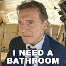 a man in a suit and tie is sitting in a car with the words i need a bathroom below him