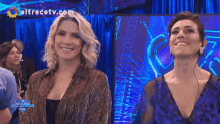 two women are smiling in front of a screen that says eltrecetv.com on it