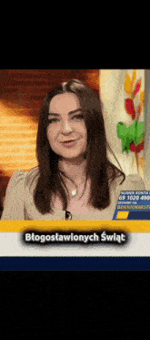 a woman is smiling in front of a yellow sign that says błogosławionych świat