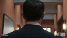 a man in a suit is walking down a hallway with a daredevil born again poster in the background