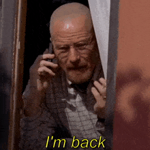 a bald man talking on a cell phone with the words i 'm back behind him