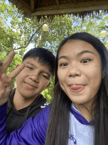 a boy and a girl are posing for a picture and the girl is wearing a purple nike shirt