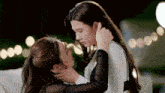 two women are kissing each other while sitting on a couch at night .