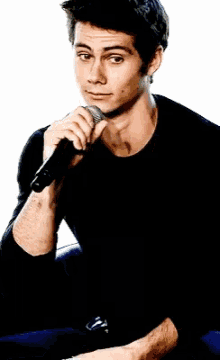 a man in a black shirt is holding a microphone to his nose