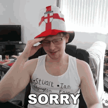a man wearing a hat and a tank top with the word sorry on it