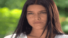 a woman with long dark hair is looking at the camera with a serious look on her face
