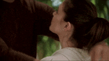 a man and a woman are kissing in front of a tree .