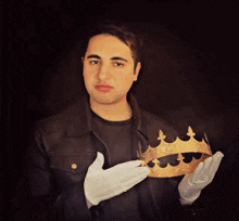 a man in white gloves holds a gold crown