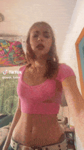 a woman in a pink crop top and jeans is standing in a room .