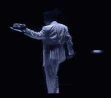 a man in a white suit is kneeling down while holding a microphone .