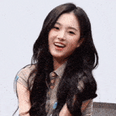 a woman with long black hair wearing a striped shirt smiles