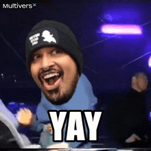 a man wearing a beanie and a blue hoodie is making a funny face and the word yay is above him
