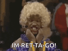a woman in a wig is holding her hands to her face and says `` im ret-ta-go '' .