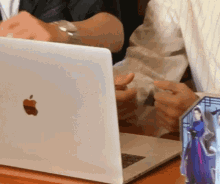 a person is typing on an apple laptop next to a picture of a woman in a blue dress