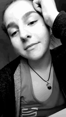 a black and white photo of a woman wearing a necklace with an owl pendant