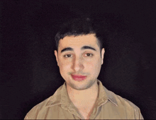 a man in a tan shirt is making a face