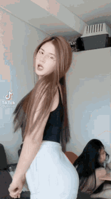 a woman in a black tank top and white shorts is dancing in a room