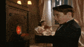 a young boy in a tuxedo looks at a red clock