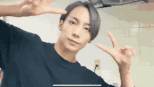 a man in a black shirt is giving a peace sign