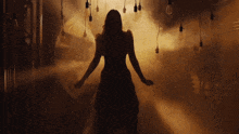 a silhouette of a woman in a dark room with smoke coming out of the ceiling