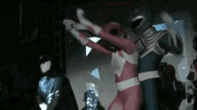 a group of power rangers are standing next to each other on a stage in a dark room .
