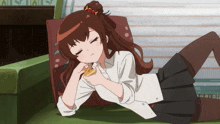 a girl is laying on a couch with her eyes closed and eating a cookie