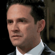 a man in a suit and tie looks at the camera with a serious look on his face