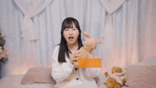 a girl is holding a stuffed animal with chinese writing on the bottom right