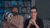 a man with a beard and glasses holds a soccer ball