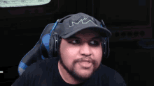 a man with a beard wearing headphones and a hat that has the letter m on it