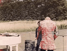 a woman in a red coat is standing next to a white piano