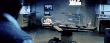a person is laying on an operating table in a dark room with a monitor behind them .