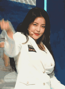 a woman wearing a white jacket and a microphone is dancing on a stage