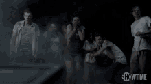 a group of people standing in a dark room with showtime written on the bottom of the screen