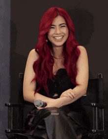 a woman with red hair is sitting in a chair with a microphone in her hand