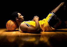 a basketball player is laying on the floor with his legs crossed and his head on a basketball .