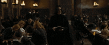 a man in a black robe is reading a book in front of a crowd