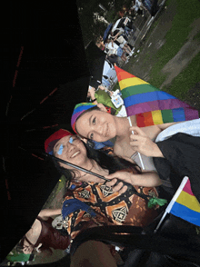 a woman holding a rainbow flag stands next to a man holding an umbrella