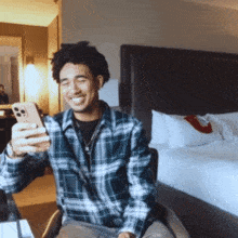 a man in a plaid shirt is taking a picture of himself with his phone