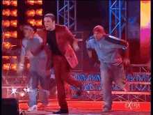 a group of men are dancing on a stage with the word extra on the bottom