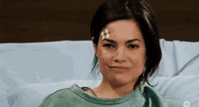 a woman is laying in a hospital bed with a bandage on her forehead